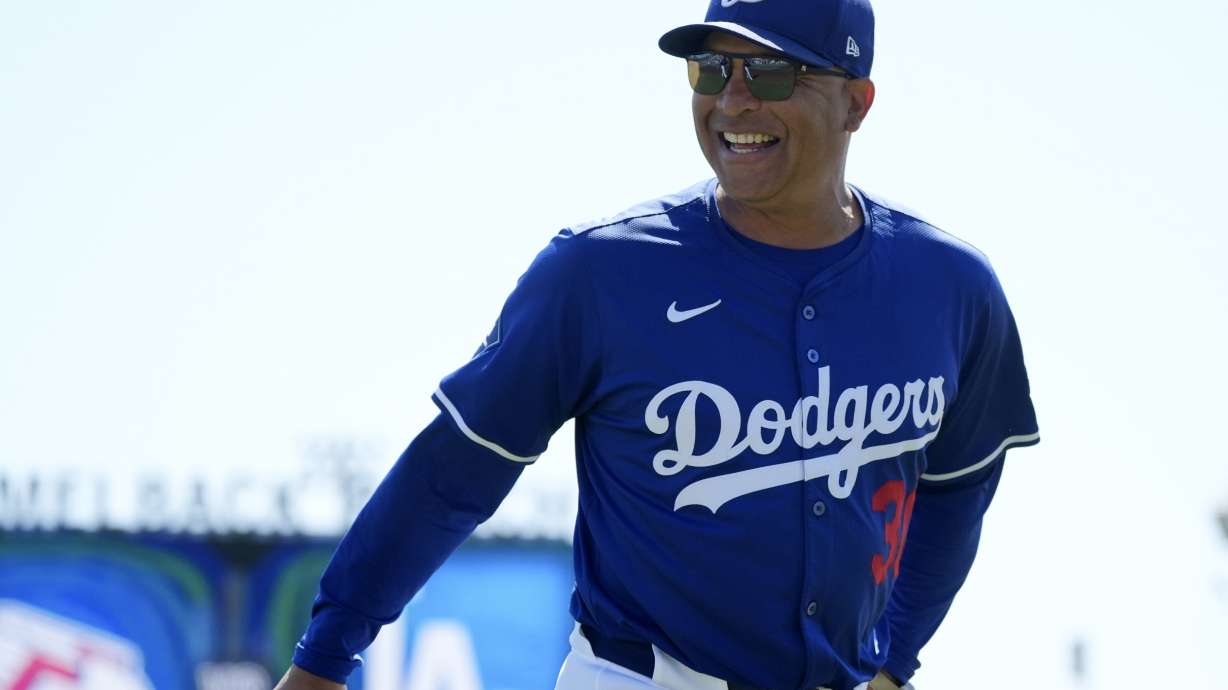 Los Angeles Dodgers manager Dave Roberts smiles at fans as he heads to the dugout prior to a spring training baseball game against the Cleveland Guardians, Tuesday, March 11, 2025, in Phoenix.