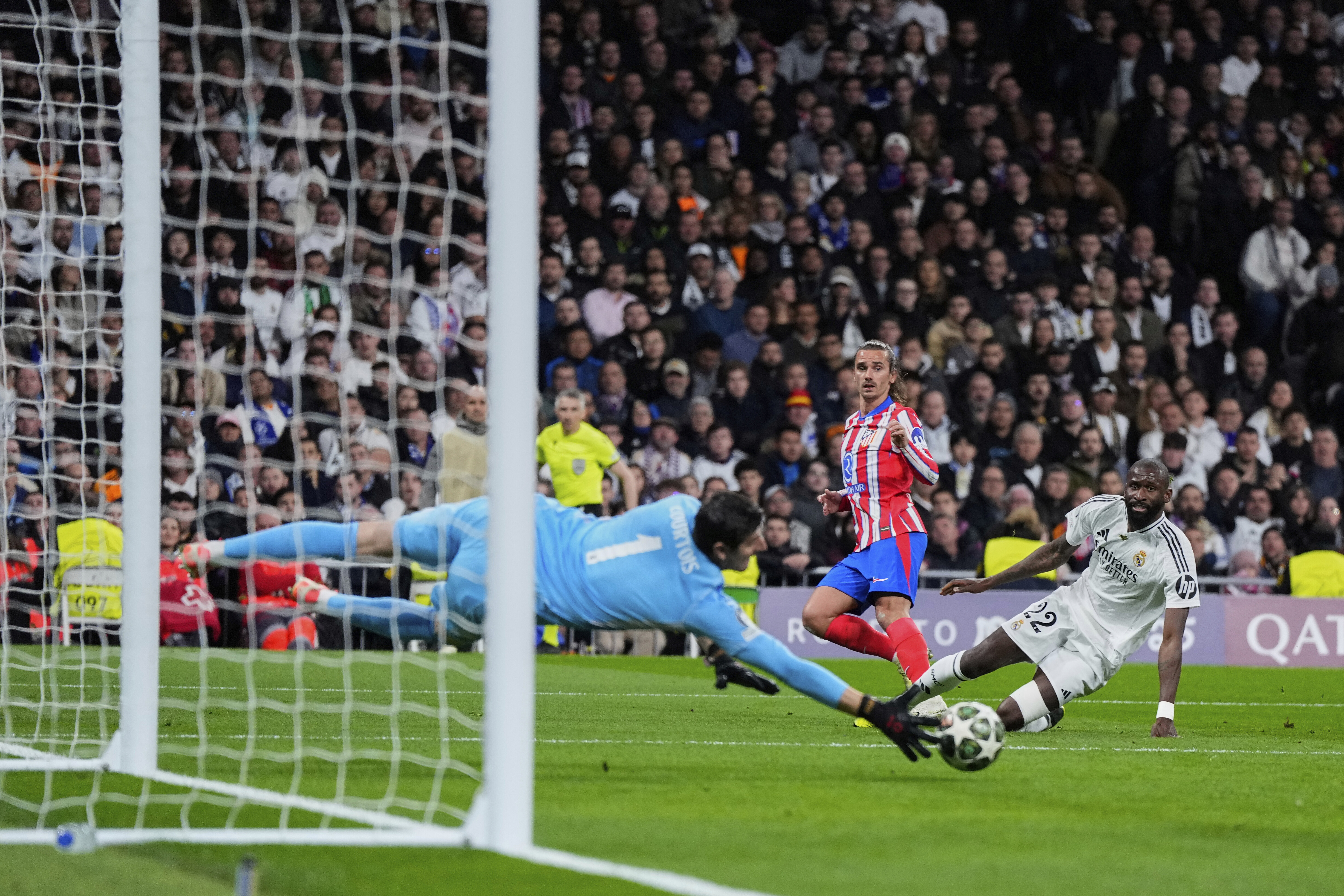 Real Madrid's goalkeeper Thibaut Courtois, left, makes a save in front Atletico Madrid's Antoine Griezmann, center, during the Champions League round of 16 first leg soccer match between Real Madrid and Atletico Madrid at the Bernebeu stadium in Madrid, Spain, Tuesday, March 4, 2025.