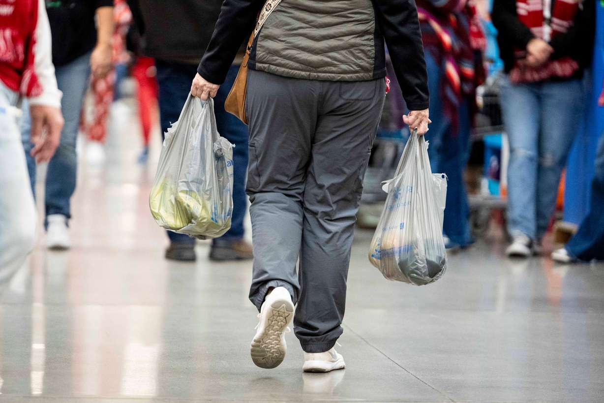 A shopper walks with bags of groceries at the South Jordan Parkway Walmart on Dec. 7, 2024.