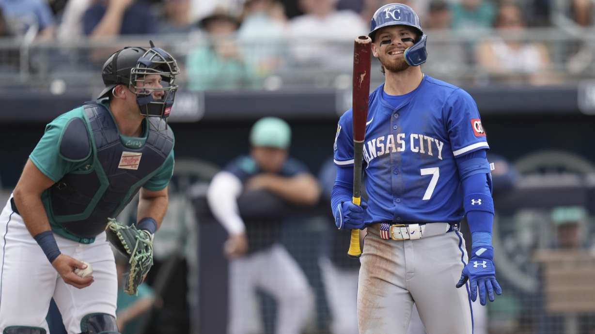 Kansas City Royals' Bobby Witt Jr. (7) grimaces after striking out as Seattle Mariners catcher Cal Raleigh holds the ball during the third inning of a spring training baseball game Wednesday, March 12, 2025, in Peoria, Ariz.
