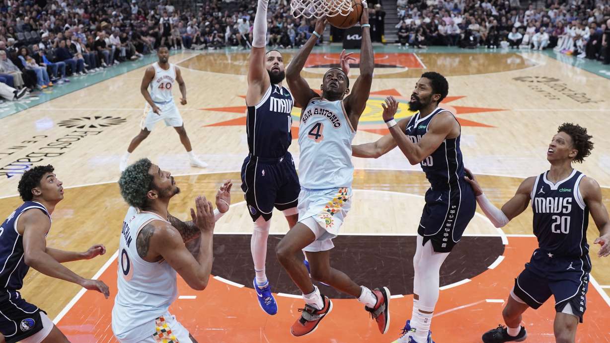 San Antonio Spurs guard De'Aaron Fox (4) scores past Dallas Mavericks forward Caleb Martin (16) during the second half of an NBA basketball game in San Antonio, Wednesday, March 12, 2025.