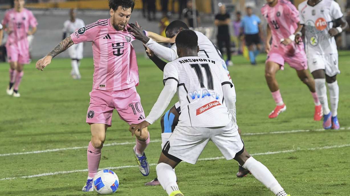Inter Miami forward Lionel Messi, left, attempts to keep the ball from Christopher Ainsworth of Jamaica's Cavalier during a CONCACAF Champions Cup soccer match in Kingston, Jamaica, Thursday, March 13, 2025.