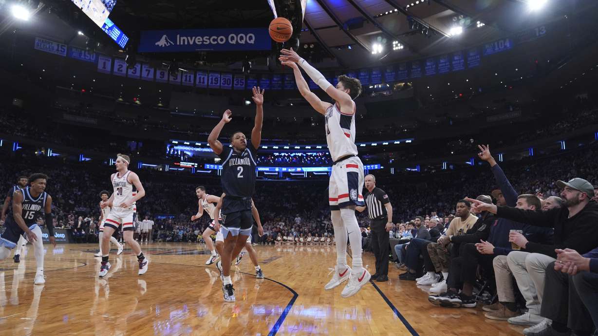 Fans watch as Villanova's Jhamir Brickus (2) runs to defend a three-point shot by UConn's Aidan Mahaney (20) during the first half of an NCAA college basketball game at the Big East basketball tournament Thursday, March 13, 2025, in New York.