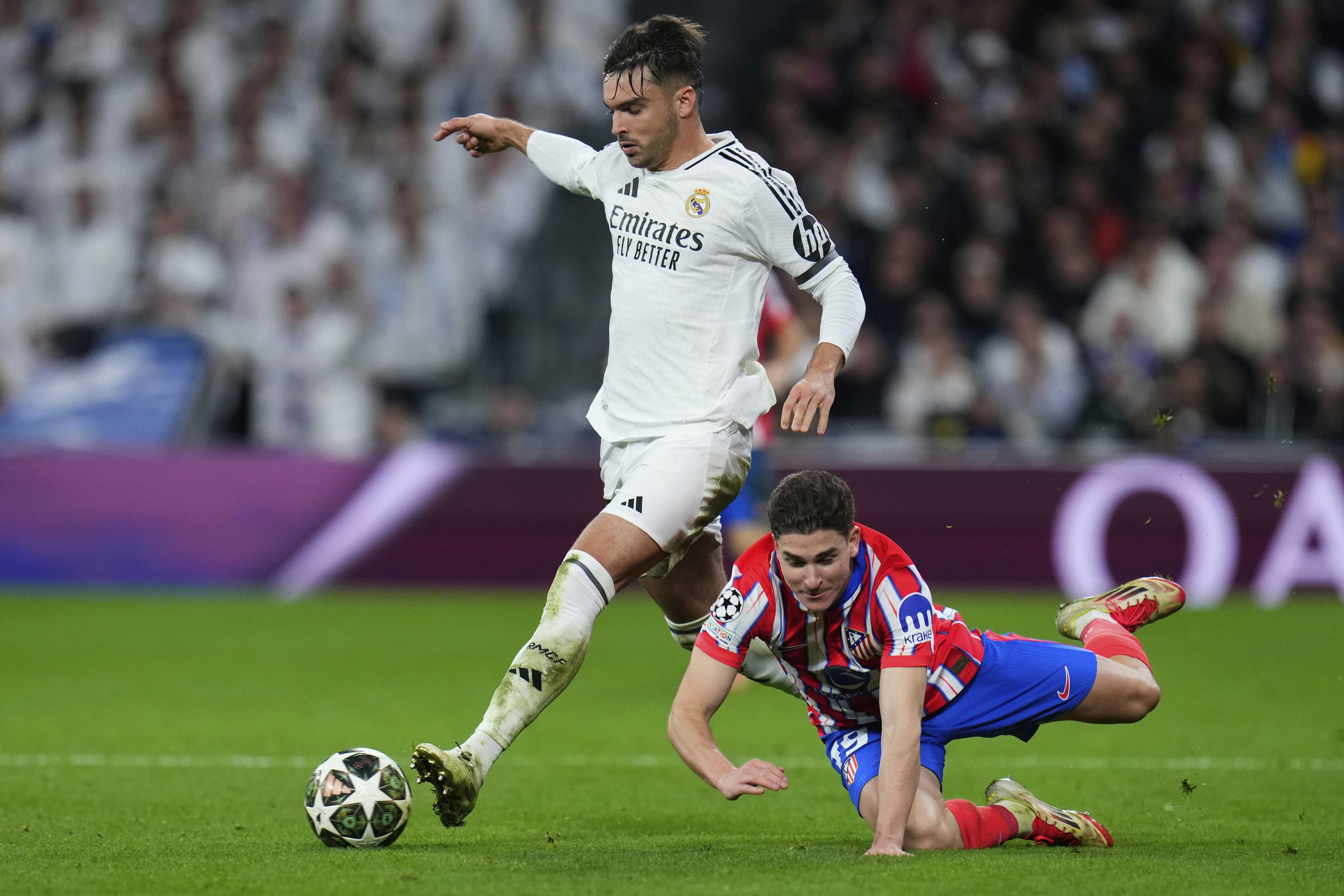 Atletico Madrid's Julian Alvarez, right, is challenged by Real Madrid's Raul Asencio during the Champions League round of 16 first leg soccer match between Real Madrid and Atletico Madrid at the Bernebeu stadium in Madrid, Spain, Tuesday, March 4, 2025.