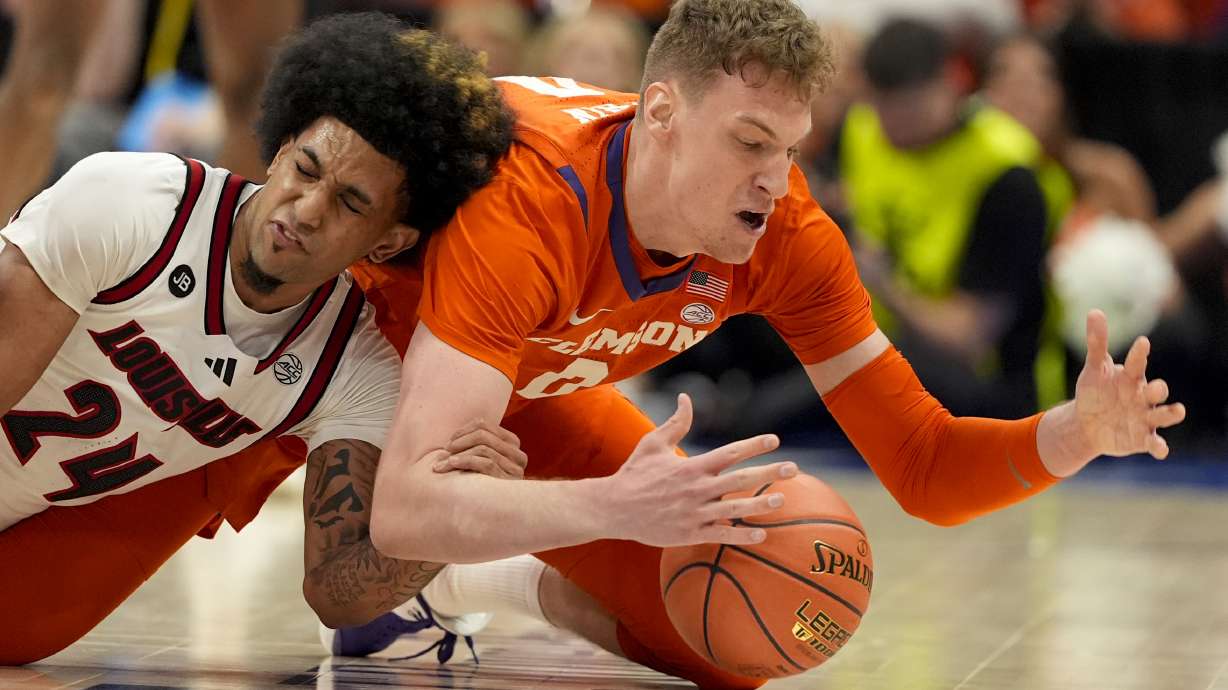 Louisville guard Chucky Hepburn and Clemson center Viktor Lakhin vie for a loose ball during the second half of an NCAA college basketball game in the semifinals of the Atlantic Coast Conference tournament, Friday, March 14, 2025, in Charlotte, N.C.