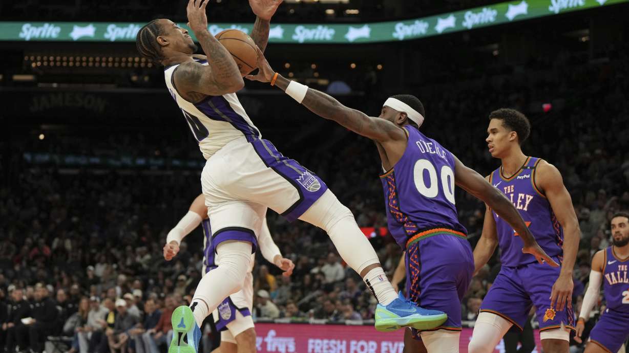 Phoenix Suns forward Royce O'Neale (00) fouls Sacramento Kings forward DeMar DeRozan during the first half of an NBA basketball game, Friday, March 14, 2025, in Phoenix.