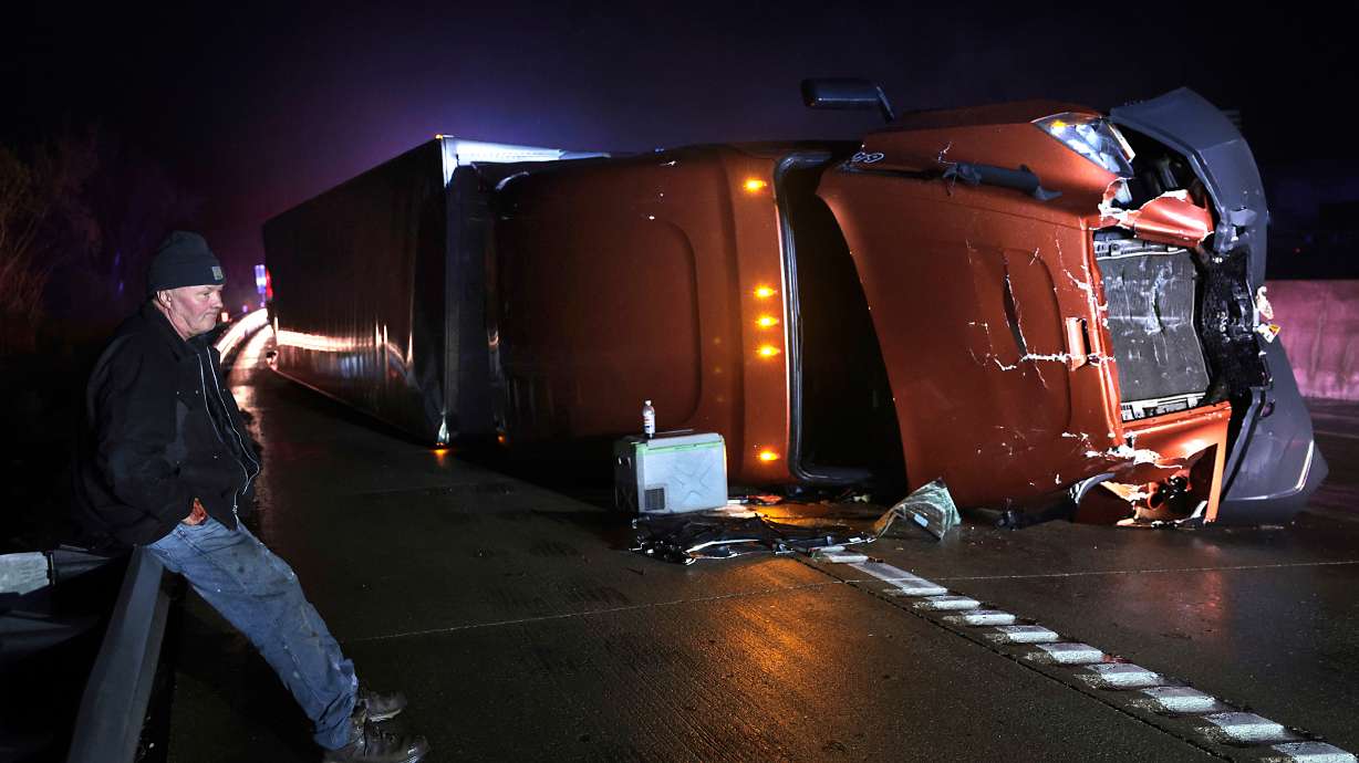 Mark Nelson, of Wis., waits with his tractor-trailer after it overturned during high winds and a possible tornado on Interstate 44 westbound at Villa Ridge, Missouri, Friday.