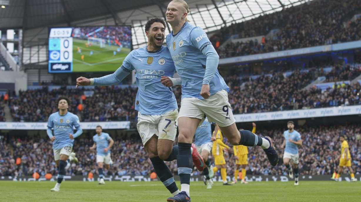 Manchester City's Erling Haaland, right, celebrates with his teammate Omar Marmoush after scoring his side's opening goal during the English Premier League soccer match between Manchester City and Brighton and Hove Albion at Etihad stadium in Manchester, England, Saturday, March 15, 2025.