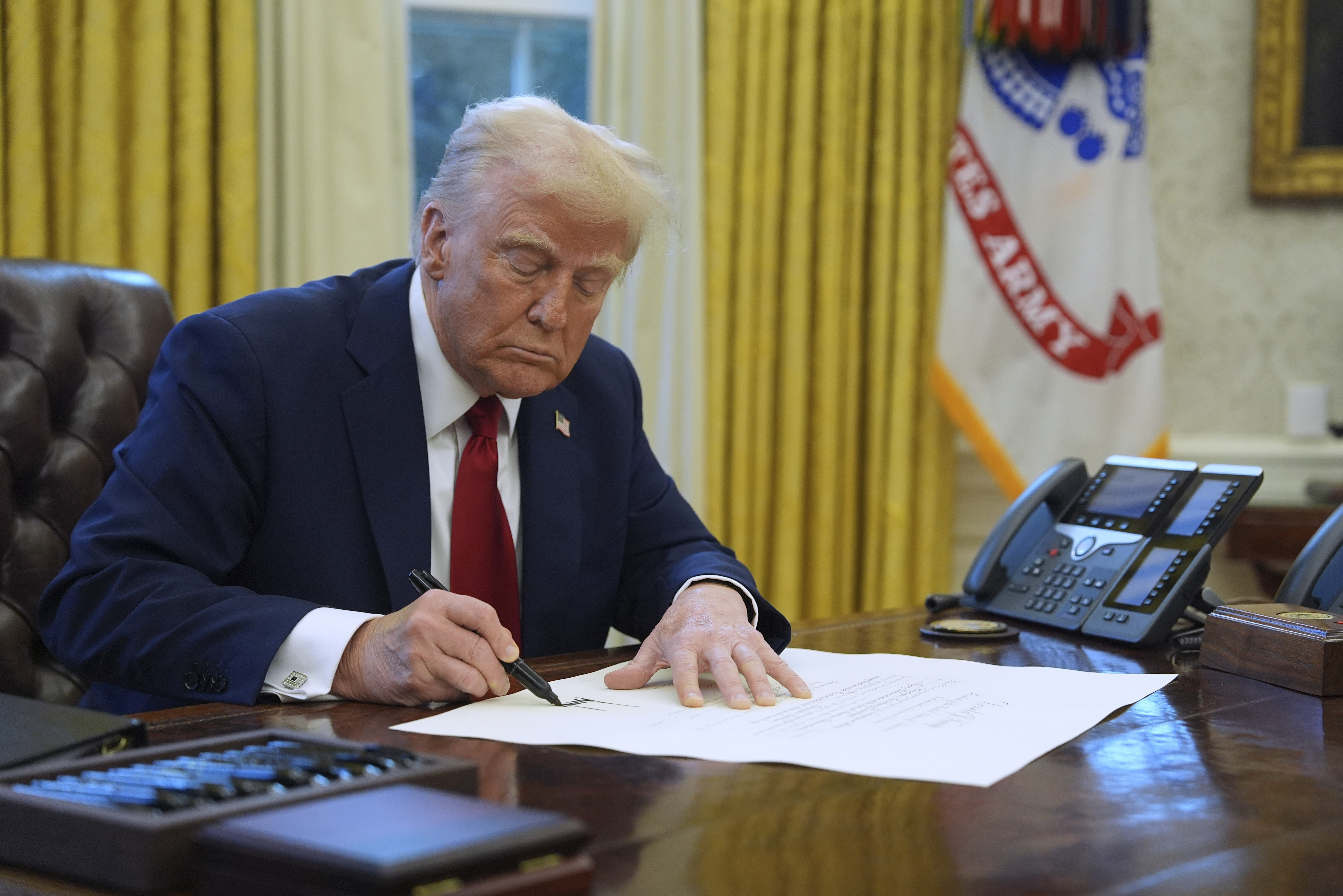 President Donald Trump signs a document in the Oval Office at the White House in January. Trump signed legislation to fund the government until September Saturday.