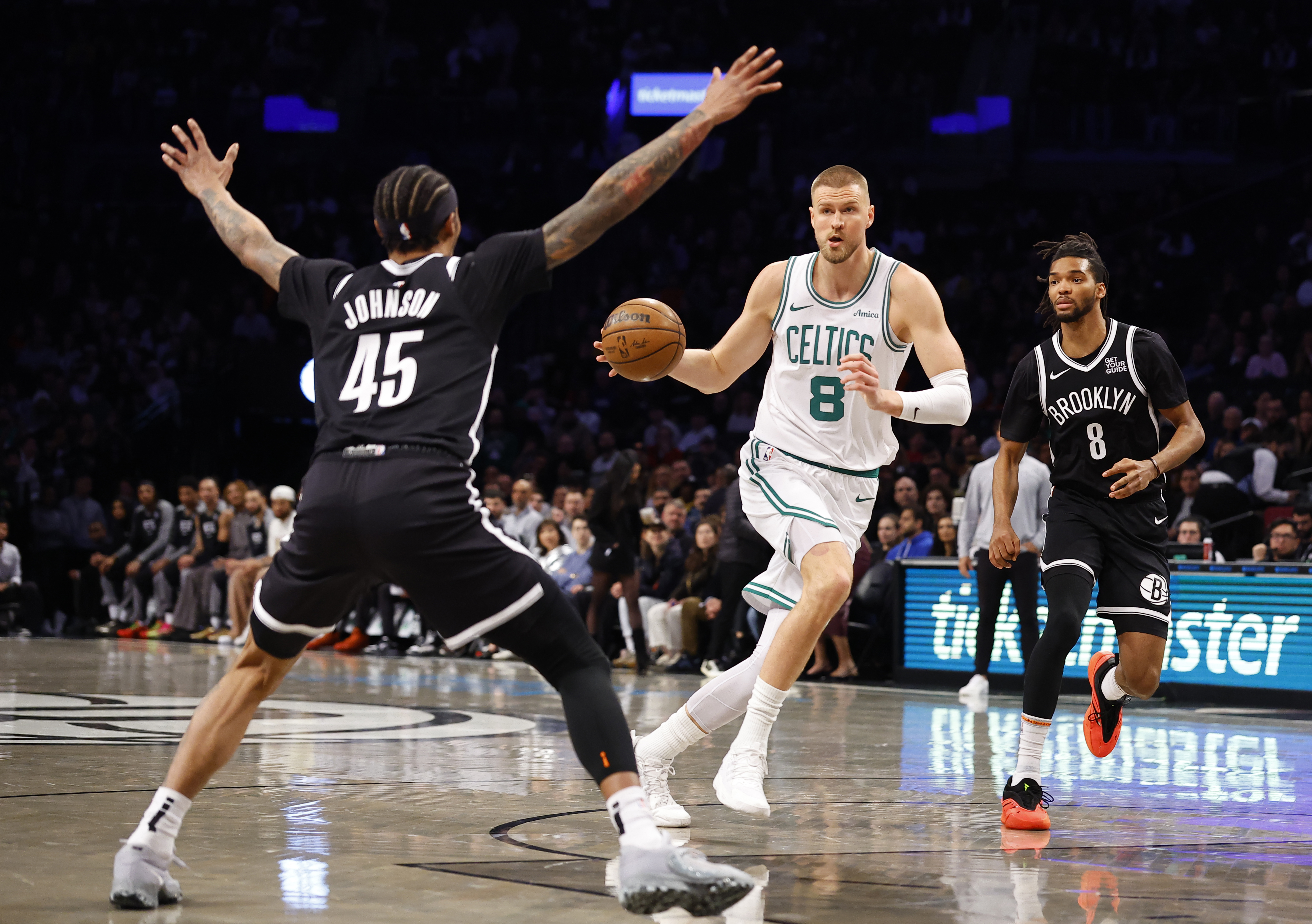 Boston Celtics' Kristaps Porzingis (8) drives to the basket against Brooklyn Nets' Keon Johnson (45) and Ziaire Williams (8) during the first half of an NBA basketball game, Saturday, March 15, 2025, in New York.