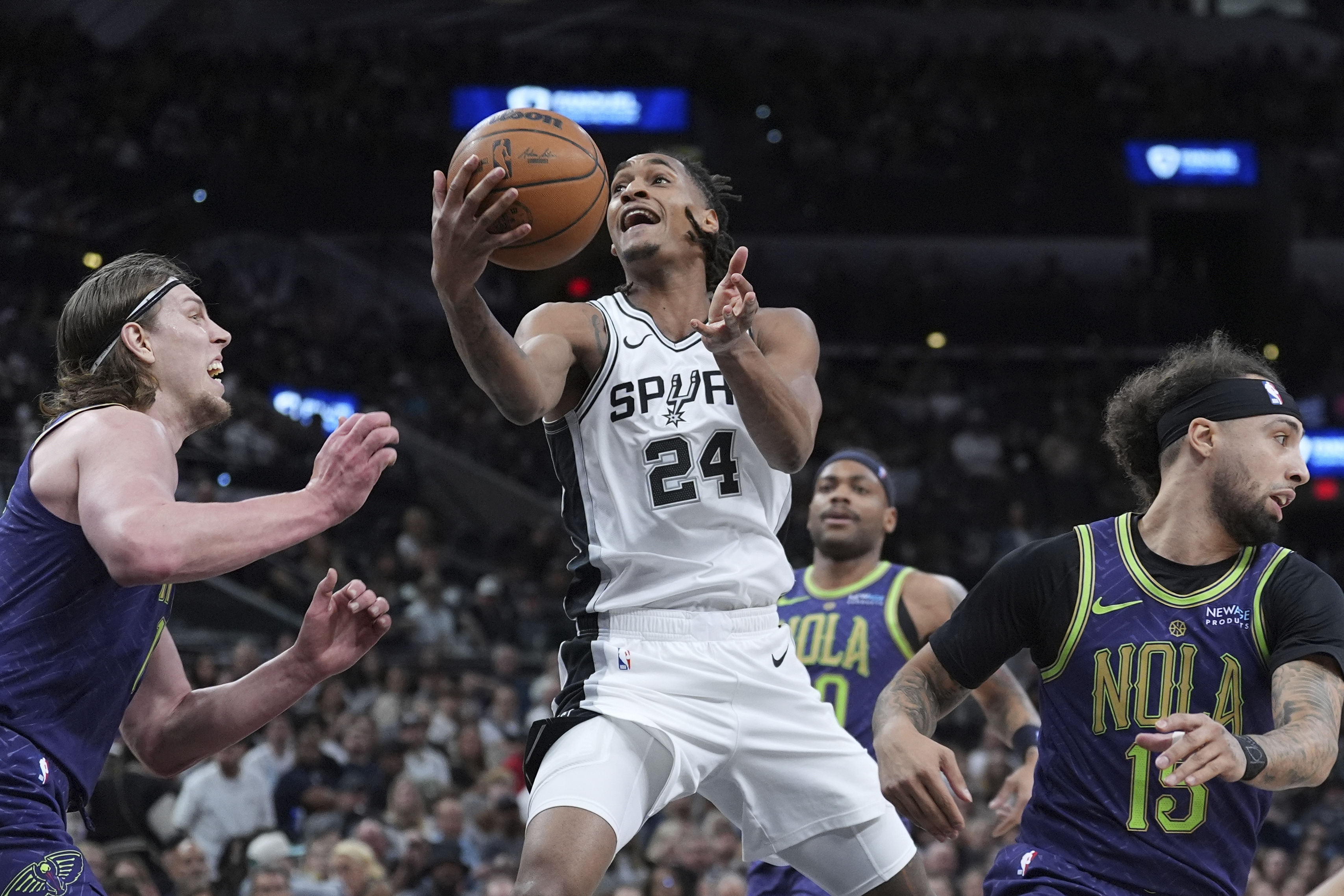 San Antonio Spurs guard Devin Vassell (24) drives to the basket against New Orleans Pelicans forward Kelly Olynyk, left, during the first half of an NBA basketball game in San Antonio, Saturday, March 15, 2025.