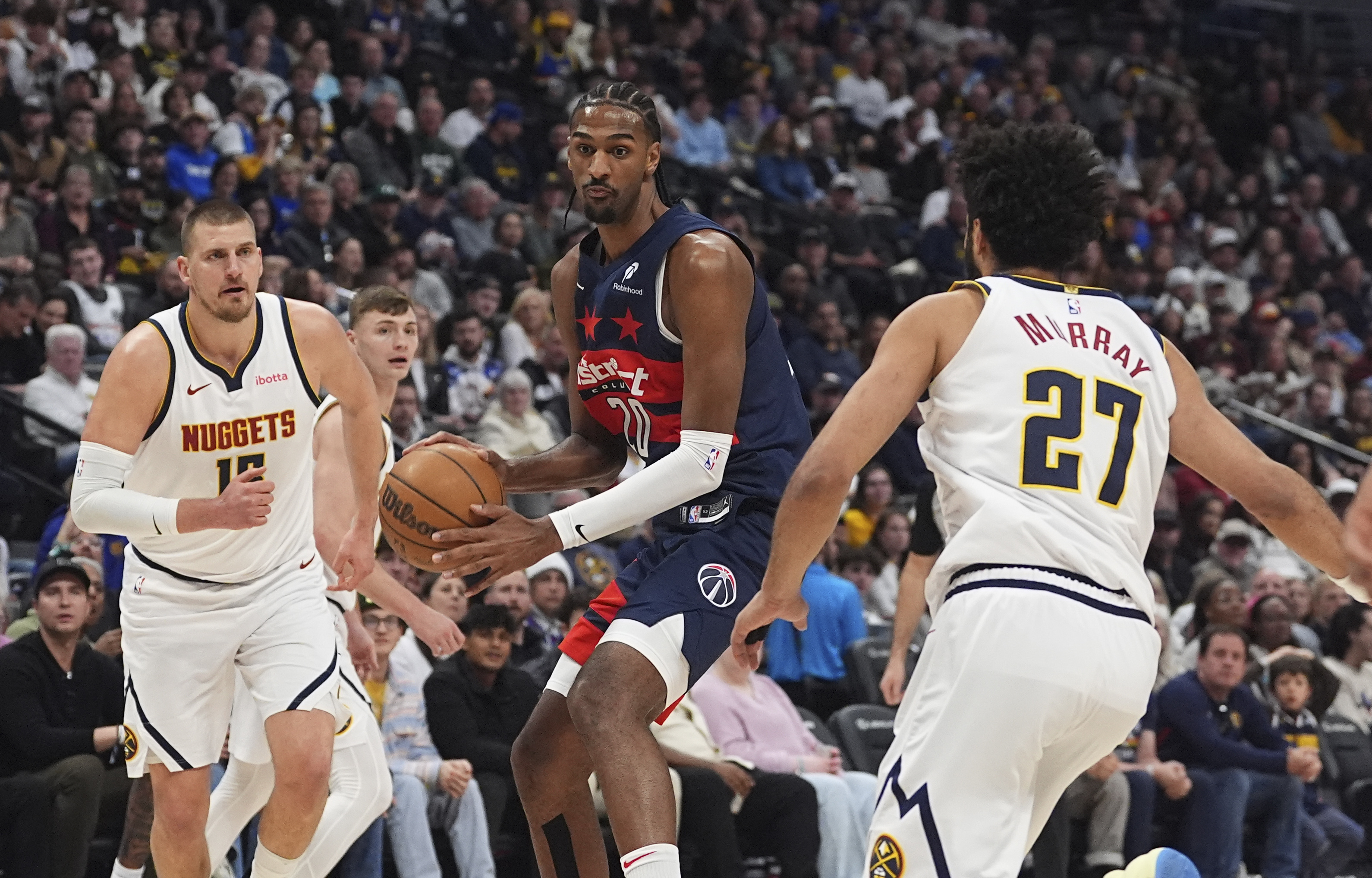 Washington Wizards forward Alex Sarr, center, drives to the basket between Denver Nuggets center Nikola Jokic, left, and guard Jamal Murray in the first half of an NBA basketball game Saturday, March 15, 2025, in Denver.