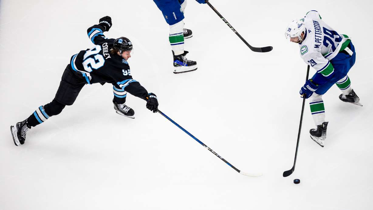 Utah Hockey Club center Logan Cooley (92) tries to gain possession of the puck from Vancouver Canucks defenseman Marcus Pettersson (29) during an NHL game at the Delta Center in Salt Lake City on Sunday, Feb. 23, 2025.