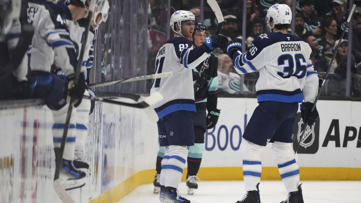Winnipeg Jets left wing Kyle Connor (81) is greeted by center Morgan Barron (36) after scoring against the Seattle Kraken during the second period of an NHL hockey game Sunday, March 16, 2025, in Seattle.