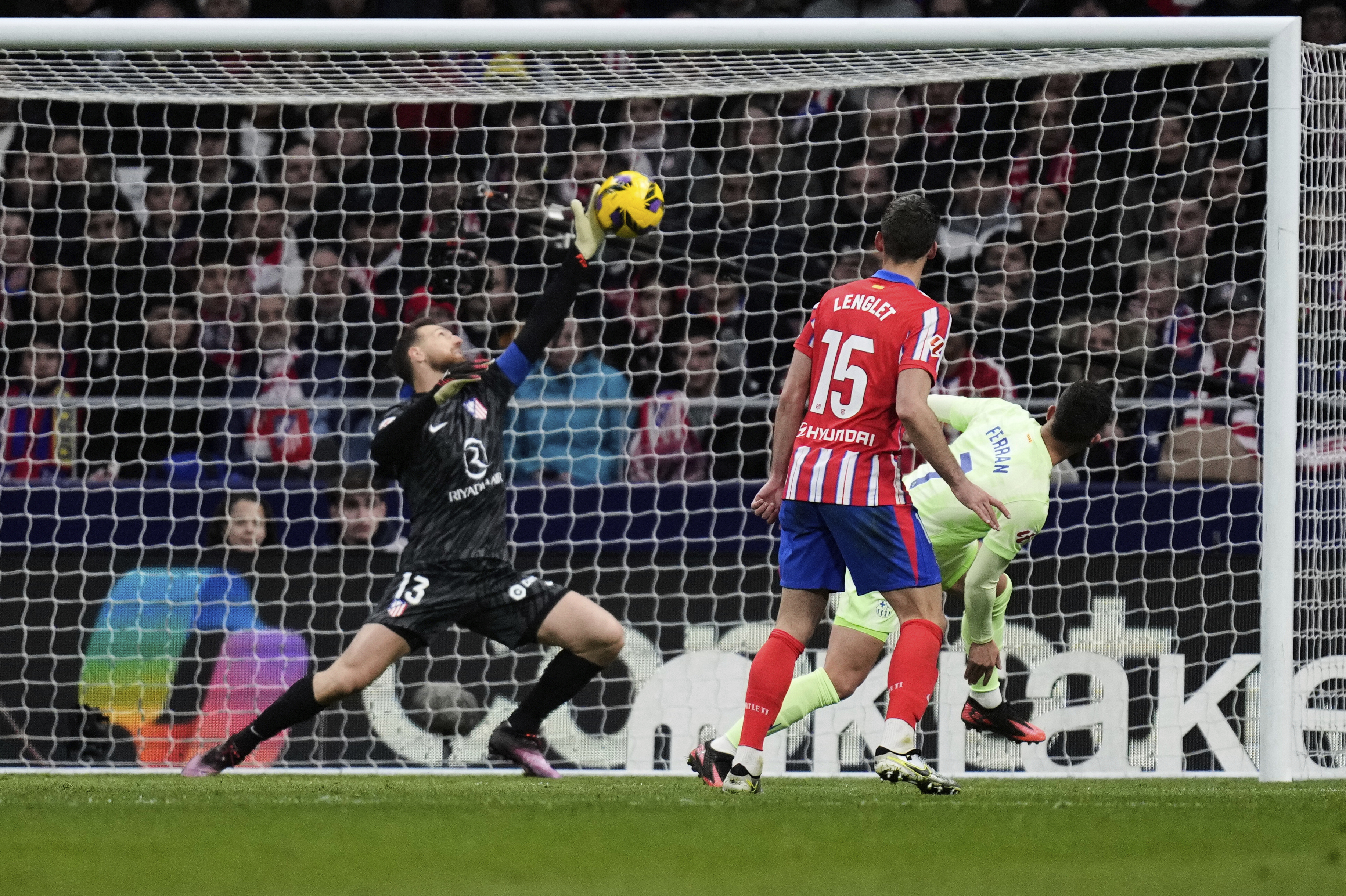 Atletico Madrid's goalkeeper Jan Oblak, left, dives but fails to save the goal from Barcelona's Ferran Torres during a La Liga soccer match between Atletico Madrid and FC Barcelona at the Metropolitano stadium in Madrid, Sunday, March 16, 2025.