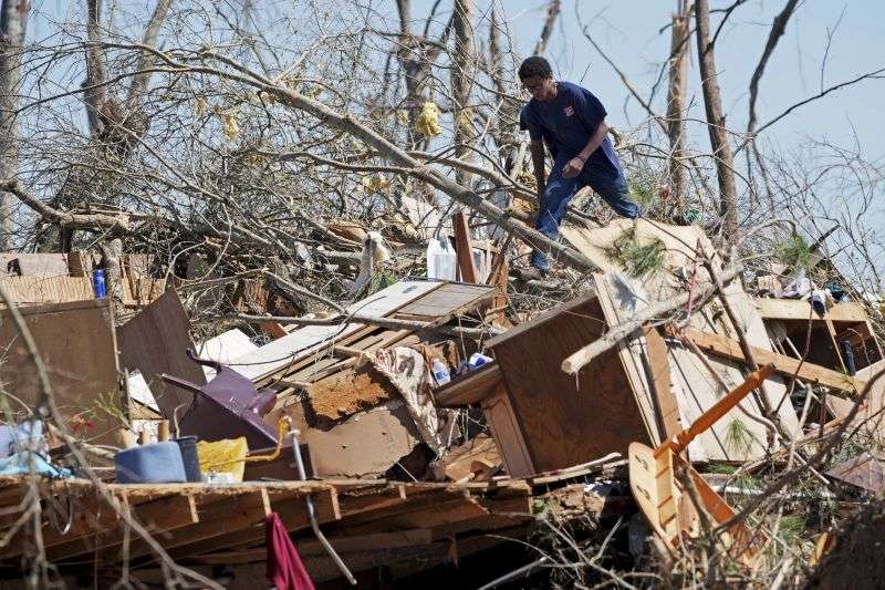 Family friend Trey Bridges, 16, climbs a mountain of tornado debris to help the Blansett family recover items not destroyed by Saturday's tornado, Sunday in Tylertown, Miss.