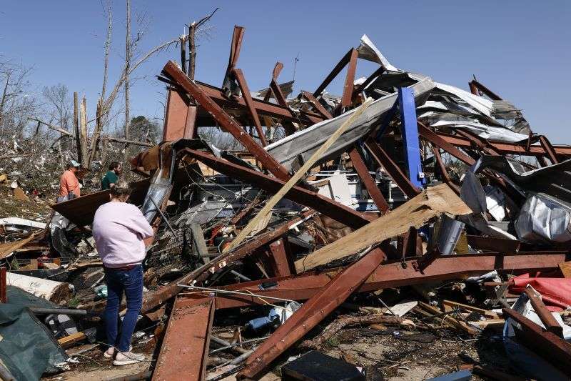 Friends and family members search for belongings in the damage after a tornado passed through the area, Sunday, in Plantersville, Ala.