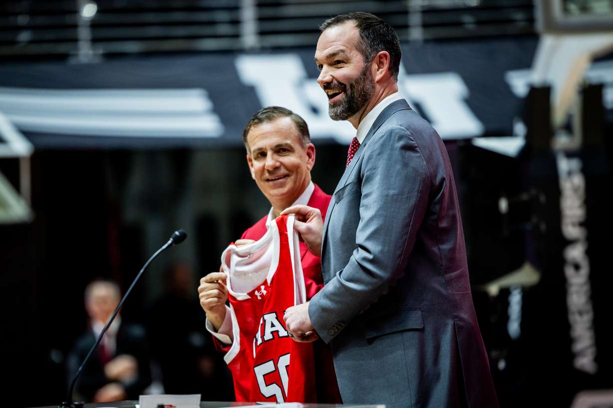 Utah Director of Athletics Mark Harlan, left, honors Alex Jensen with his jersey at a press conference to introduce Alex Jensen, right, as the new head coach for the University of Utah men's basketball team at the Jon M. Huntsman Center in Salt Lake City on Monday, March 17, 2025.
