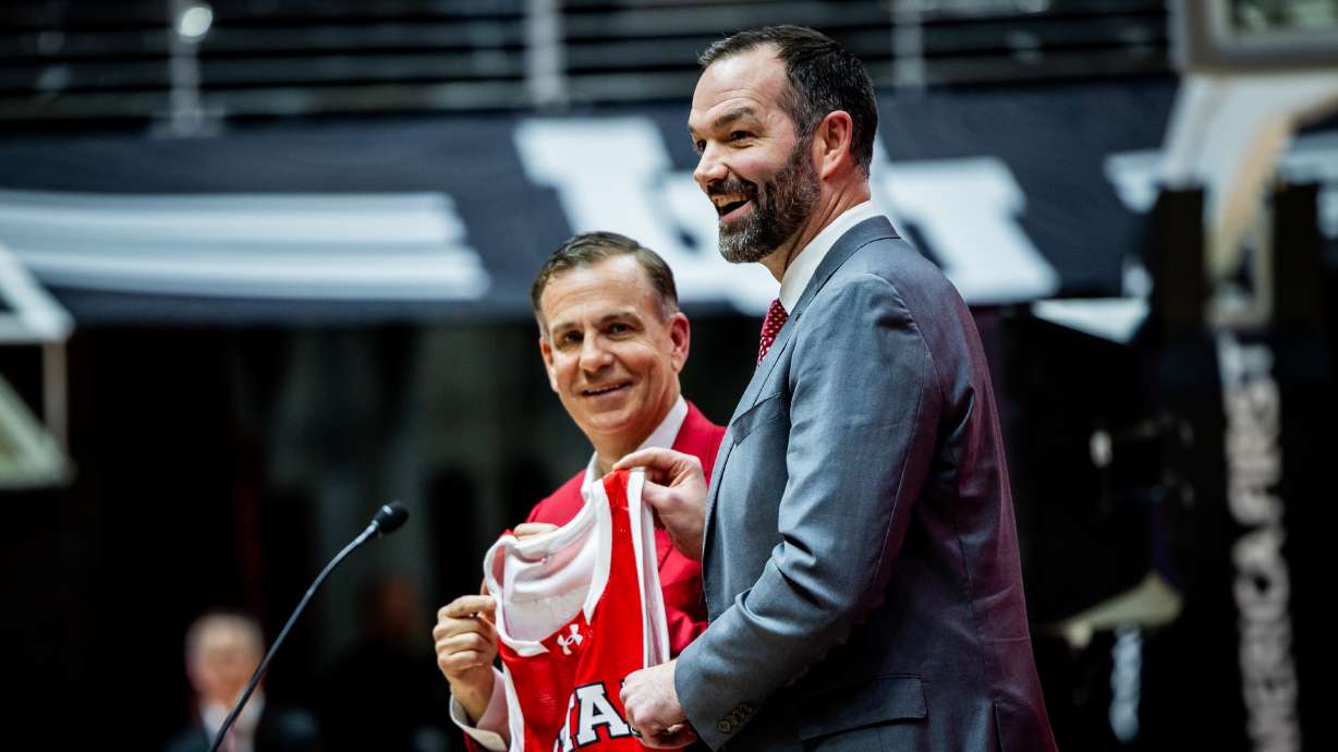 Utah Director of Athletics Mark Harlan, left, honors Alex Jensen with his jersey at a press conference to introduce Alex Jensen, right, as the new head coach for the University of Utah men's basketball team at the Jon M. Huntsman Center in Salt Lake City on Monday, March 17, 2025.