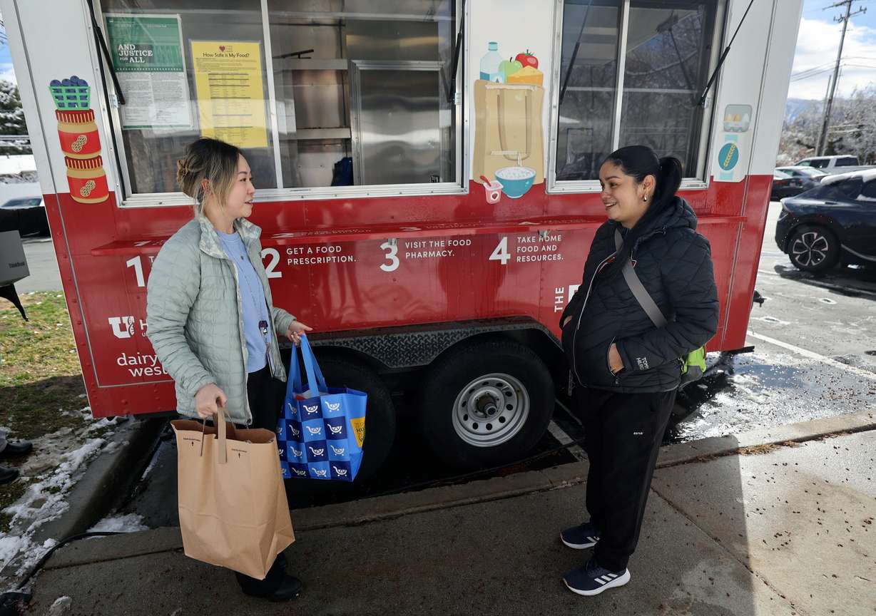 Sarah Zou, clinical dietician, gives two bags of food to Alma Rivera, who is eight months pregnant and has gestational diabetes, from the University of Utah Health Food Pharmacy trailer parked outside of Greenwood Health Center in Midvale on Friday.