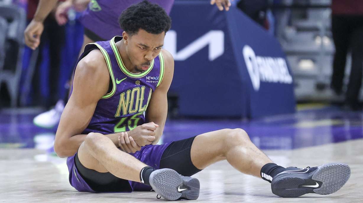 New Orleans Pelicans guard Trey Murphy III (25) holds his wrist after taking a fall on the court during the first quarter of an NBA basketball game against the Detroit Pistons in New Orleans, Monday, March 17, 2025.
