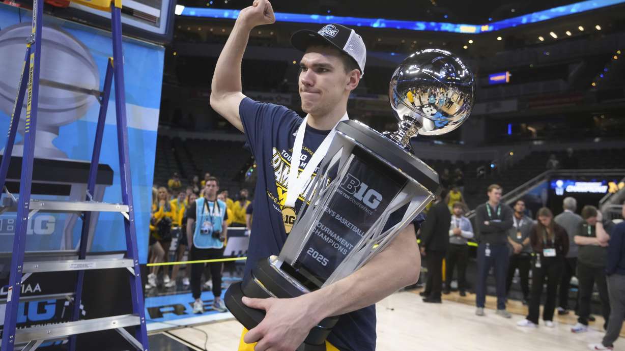 Michigan center Vladislav Goldin (50) carries the trophy after an NCAA college basketball game against Wisconsin in the championship of the Big Ten Conference tournament in Indianapolis, Sunday, March 16, 2025.