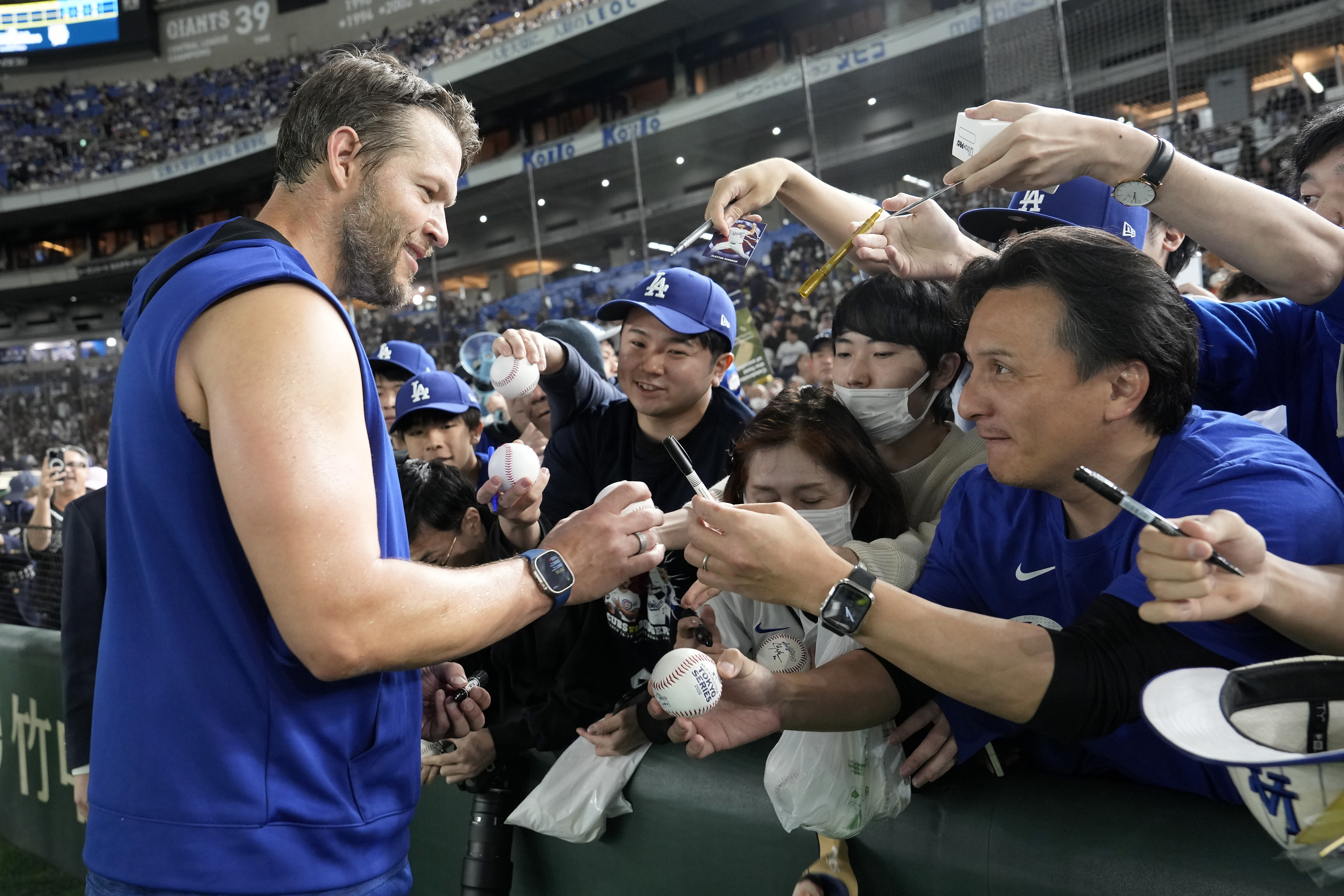 Los Angeles Dodgers pitcher Clayton Kershaw, left, signs autographs for fans before an MLB Japan Series exhibition baseball game against the Hanshin Tigers, Sunday, March 16, 2025, in Tokyo.