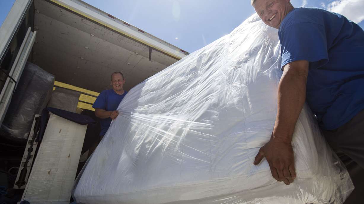 Eric Morgan, left, and Ryan Chidester, residents of The Other Side Academy, move a family's belongings into their newly constructed home in Lehi on July 18, 2017. The Other Side Movers will assist in moving donations for Furnishing Futures.