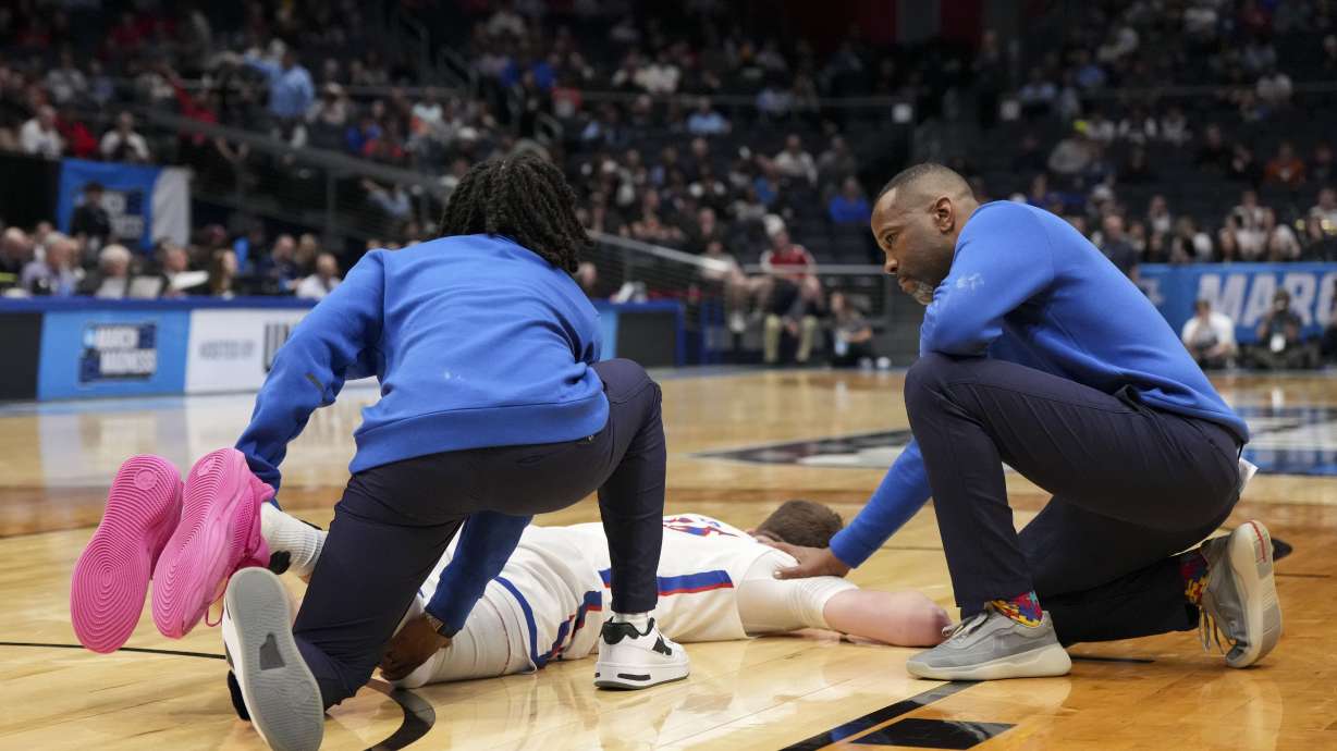 American University head coach Duane Simpkins, right, comforts player Matt Rogers after an injury during the first half of a First Four college basketball game against Mount St. Mary's in the NCAA Tournament, Wednesday, March 19, 2025, in Dayton, Ohio.