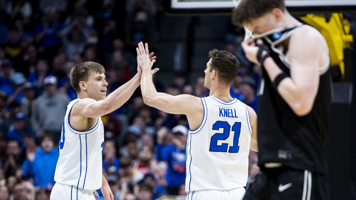 BYU Cougars guard Trevin Knell (21) and guard Dallin Hall (30) high-five after a play as Virginia Commonwealth Rams guard Max Shulga (11) walks in the foreground during a first-round college basketball game in the NCAA Tournament held at Ball Arena in Denver, Colo., on Thursday, March 20, 2025.