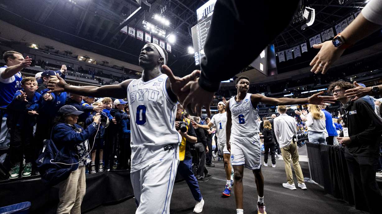 BYU Cougars forward Mawot Mag (0) and forward Kanon Catchings (6) high-five fans after defeating the Virginia Commonwealth Rams during a first-round college basketball game in the NCAA Tournament held at Ball Arena in Denver, Colo., on Thursday, March 20, 2025.