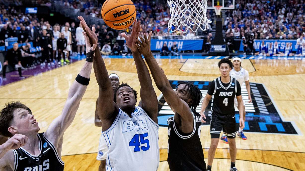 BYU Cougars center Fousseyni Traore (45) comes down with an offensive rebound while guarded by Virginia Commonwealth Rams forward Luke Bamgboye, right, and guard Max Shulga (11) during a first-round college basketball game in the NCAA Tournament held at Ball Arena in Denver, Colo., on Thursday, March 20, 2025.