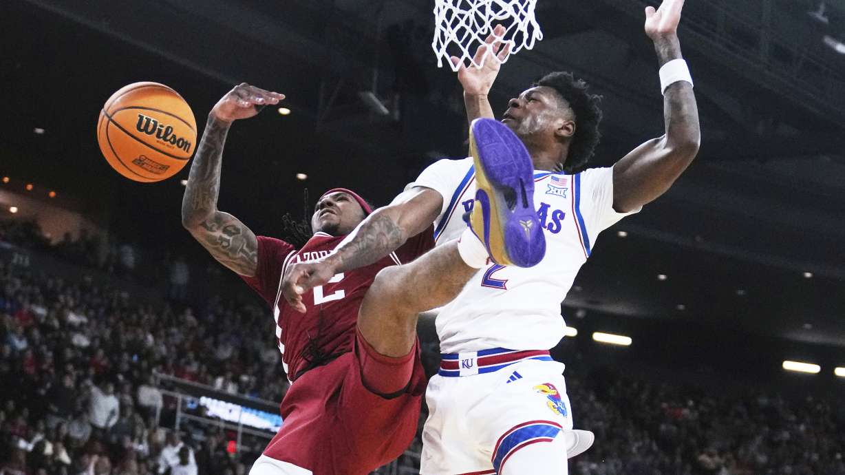 Arkansas guard Boogie Fland, left, is fouled by Kansas guard AJ Storr, right, during the first half in the first round of the NCAA college basketball tournament, Thursday, March 20, 2025, in Providence, R.I.