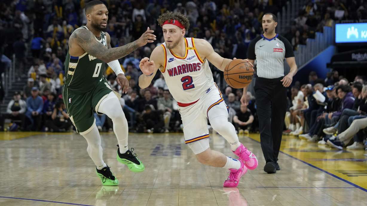 Golden State Warriors guard Brandin Podziemski (2) moves the ball while defended by Milwaukee Bucks guard Damian Lillard (0) during the second half of an NBA basketball game Tuesday, March 18, 2025, in San Francisco.