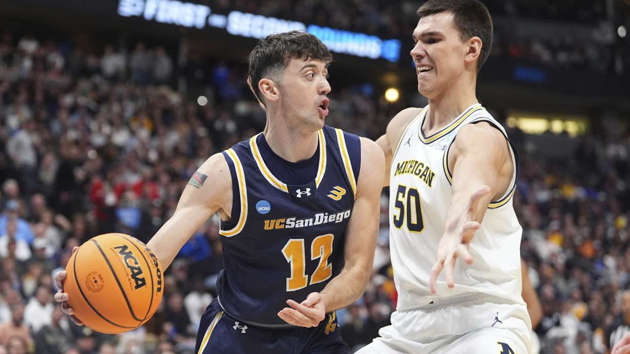 UC San Diego guard Aniwaniwa Tait-Jones, left, passes the ball as Michigan center Vladislav Goldin, right, defends during the first half in the first round of the NCAA college basketball tournament Thursday, March 20, 2025, in Denver.