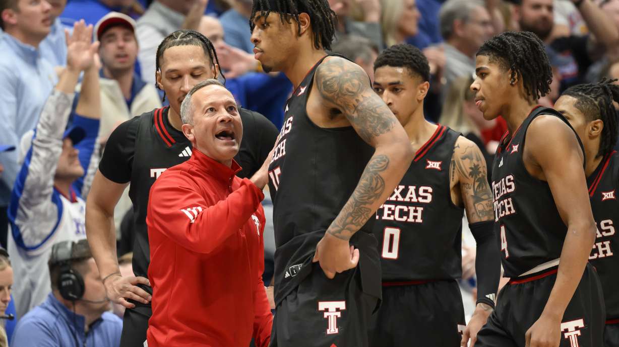 Texas Tech head coach Grant McCasland, left, talks to forward JT Toppin (15) after he fouled out against Kansas during the second half of an NCAA college basketball game in Lawrence, Kan., Saturday, March 1, 2025.