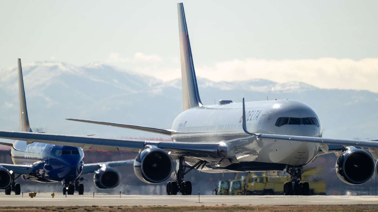 Planes line up on the taxi at the Salt Lake City International Airport on Dec. 31, 2024. A man is accused of taking a traveler's backpack and trying to take an officer's gun at the airport.