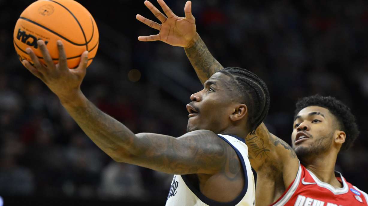 Marquette guard Kam Jones, left, drives to the basket beside New Mexico guard Donovan Dent, right, in the first half in the first round of the NCAA college basketball tournament, Friday, March 21, 2025, in Cleveland.