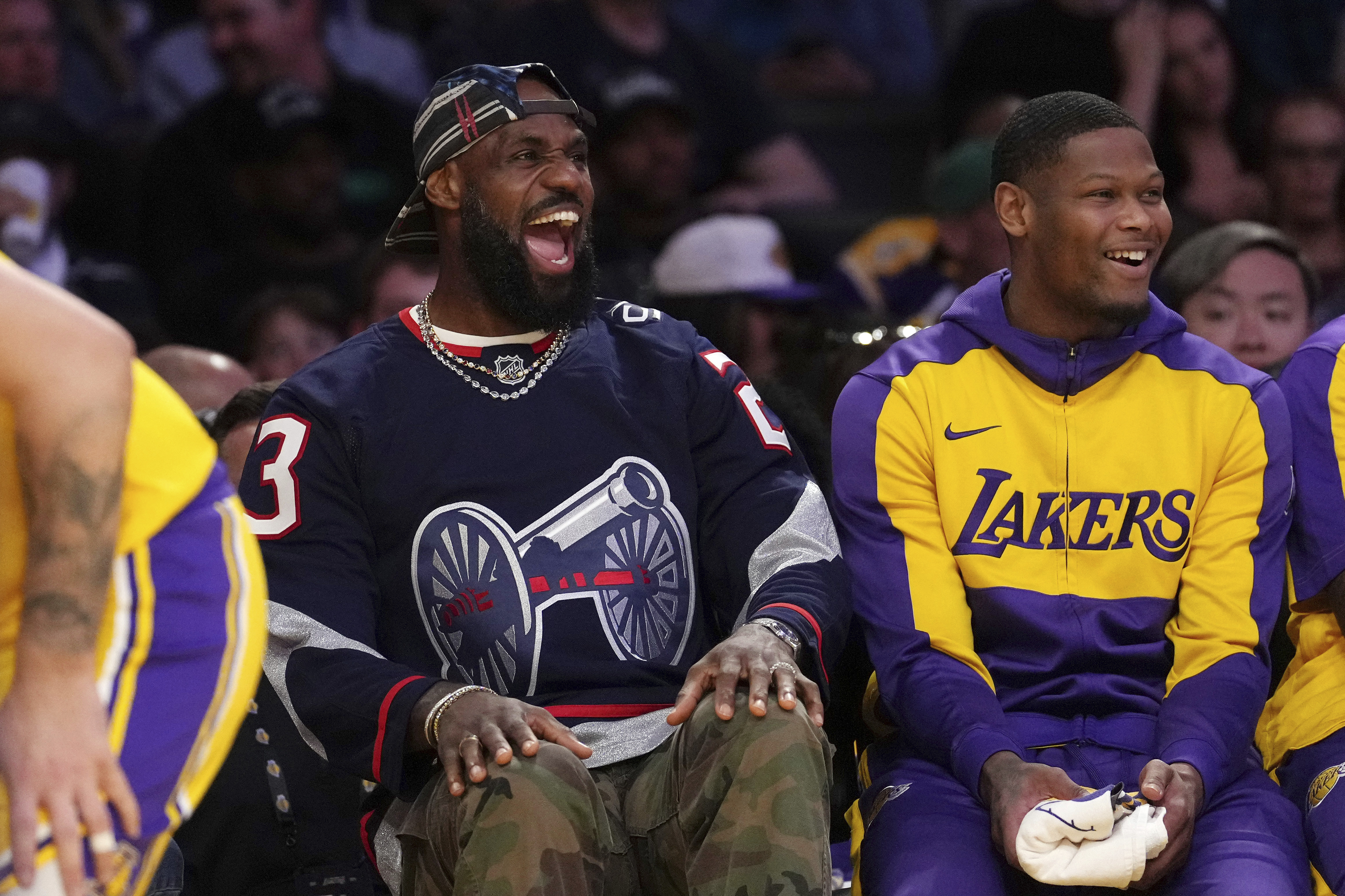 Los Angeles Lakers' LeBron James, left, laughs as he sits on the bench during the first half of an NBA basketball game against the Denver Nuggets Wednesday, March 19, 2025, in Los Angeles.