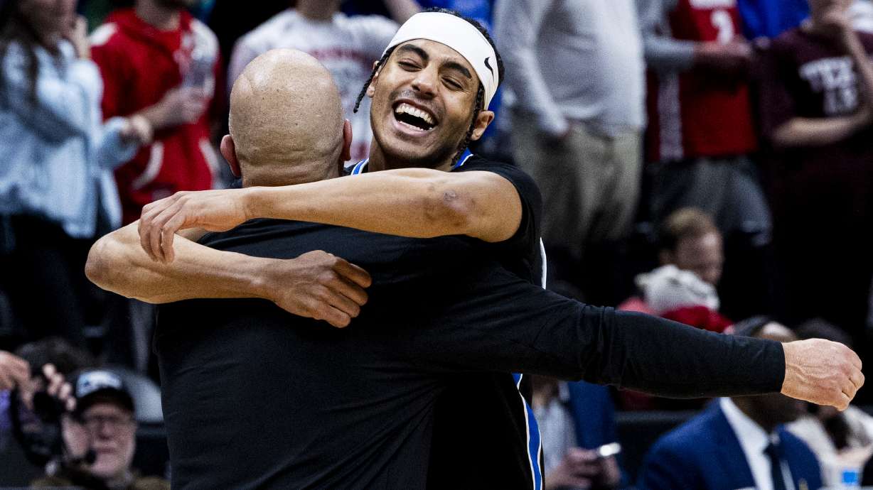 BYU Cougars guard Trey Stewart (1) hugs Greg Wrubell, the Voice of the Cougars, after they defeated the Wisconsin Badgers during a second-round college basketball game in the NCAA Tournament held at Ball Arena in Denver, Colo., on Saturday, March 22, 2025.