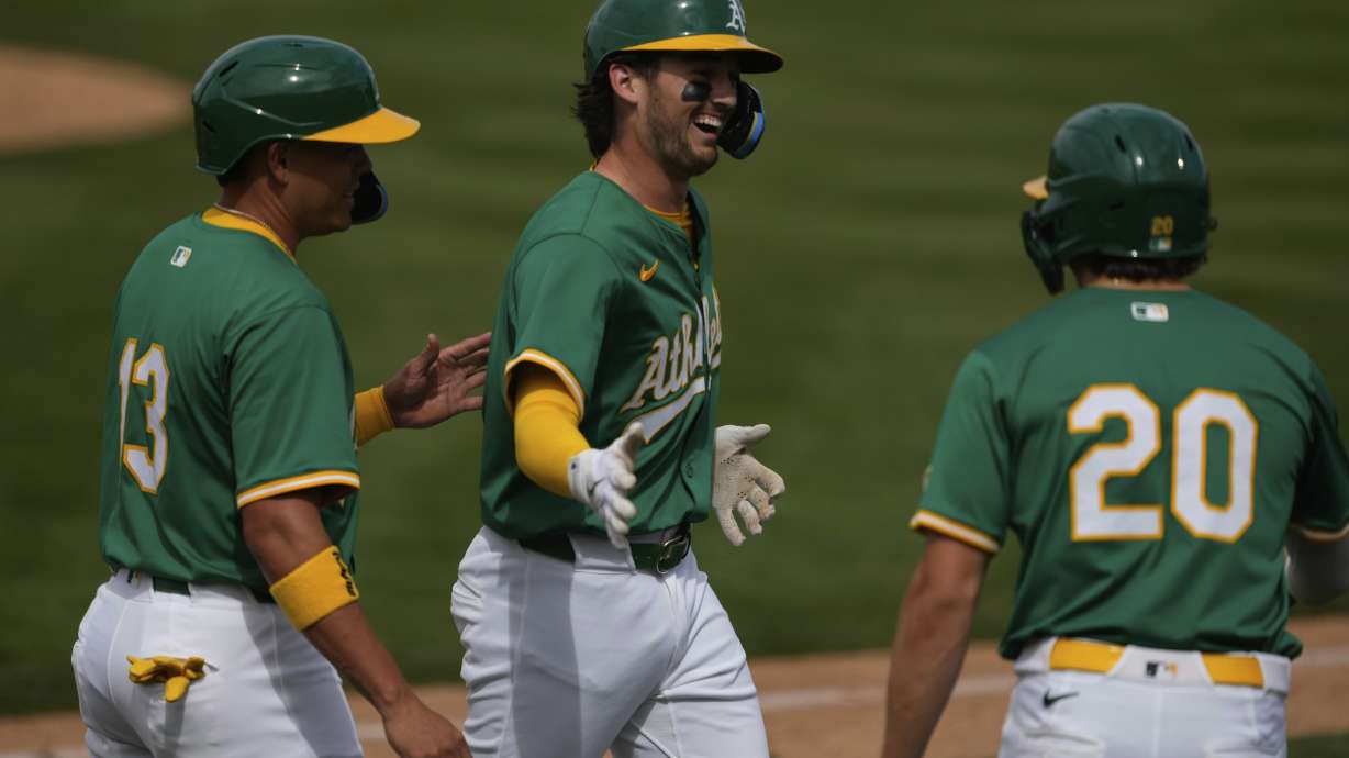 Athletics' Jacob Wilson celebrates with Zack Gelof (20) and Gio Urshela (13) after hitting a three run home run against the Seattle Mariners during the fourth inning of a spring training baseball game against the Seattle Mariners, Monday, March 17, 2025, in Mesa Ariz.