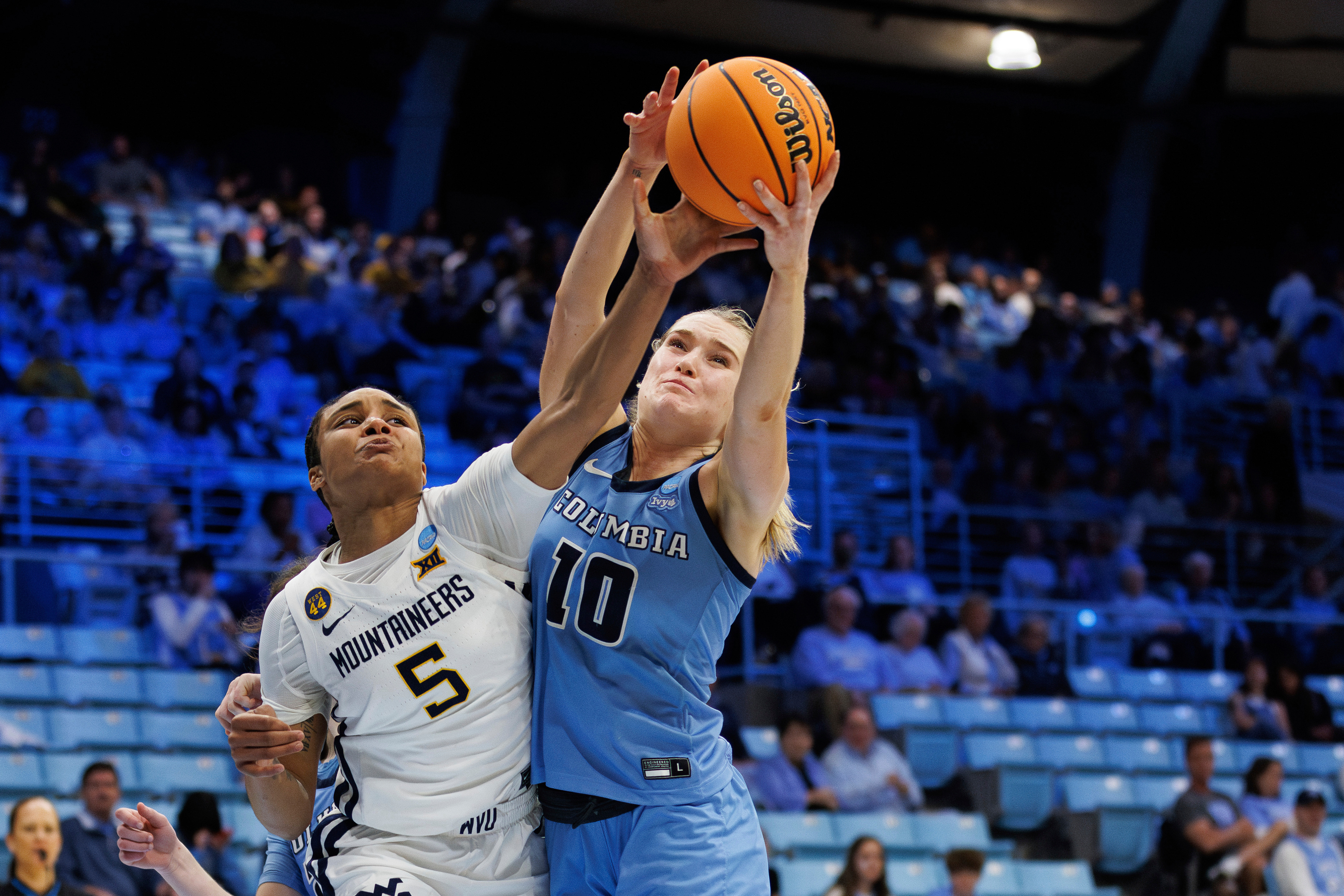 Columbia's Kitty Henderson (10) and West Virginia's Sydney Shaw (5) reach for a rebound during the second half in the first round of the NCAA college basketball tournament in Chapel Hill, N.C. Saturday, March 22, 2025.