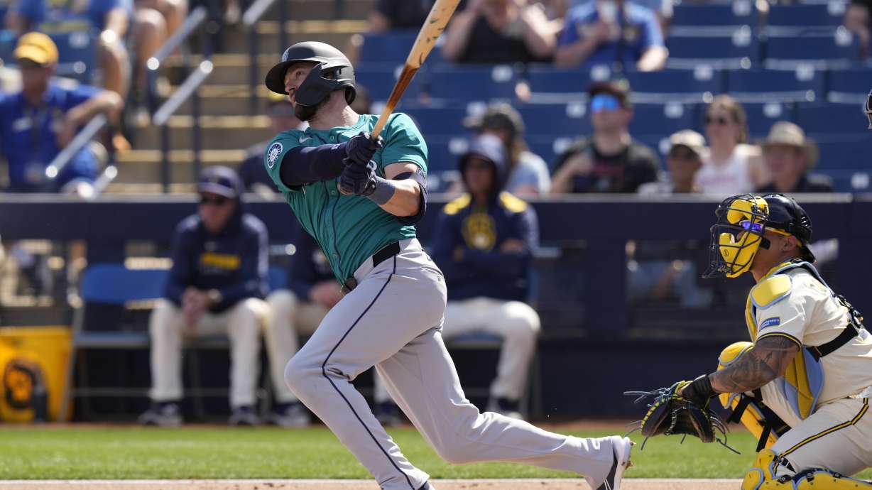 Seattle Mariners' Mitch Haniger, left, watches his solo home run during the second inning of a spring training baseball game against the Milwaukee Brewers, Monday, Feb. 24, 2025, in Phoenix.