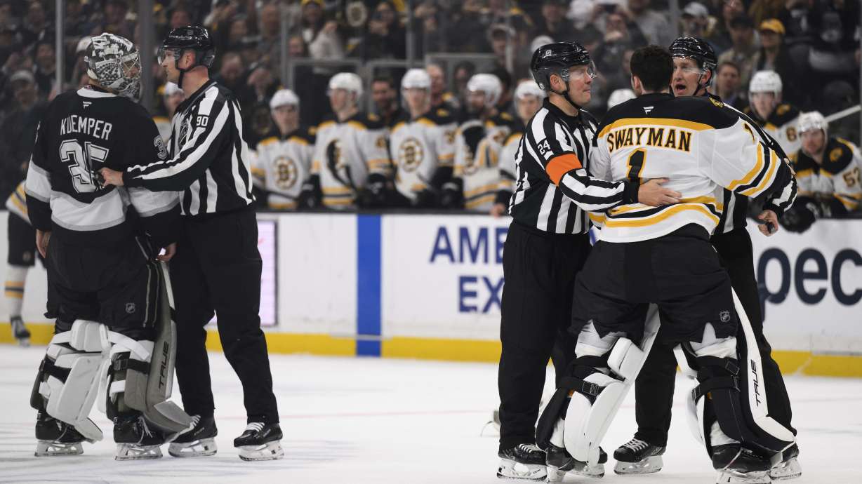 Boston Bruins goaltender Jeremy Swayman, right, is held back from fighting Los Angeles Kings goaltender Darcy Kuemper during the second period of an NHL hockey game Sunday, March 23, 2025, in Los Angeles.