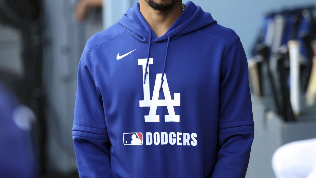 Los Angeles Dodgers' Mookie Betts walks in the dugout after getting scratched from the lineup during the first inning of a spring training baseball game against the Los Angeles Angels, Sunday, March 23, 2025, in Los Angeles.