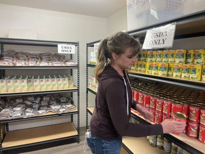 A volunteer restocks shelves at Community Action Services' Provo food bank on Monday.
