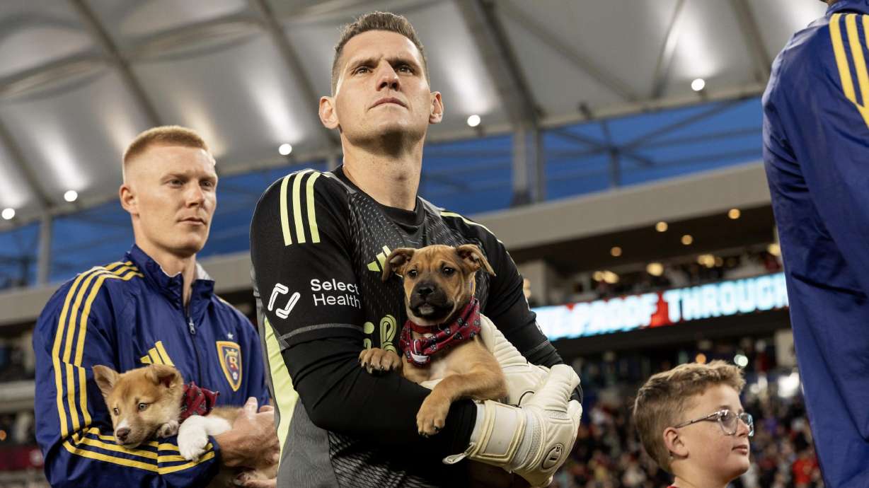 Justen Glad, left and Rafael Cabral, middle, hold dogs available for adoption from the Utah Humane Society.