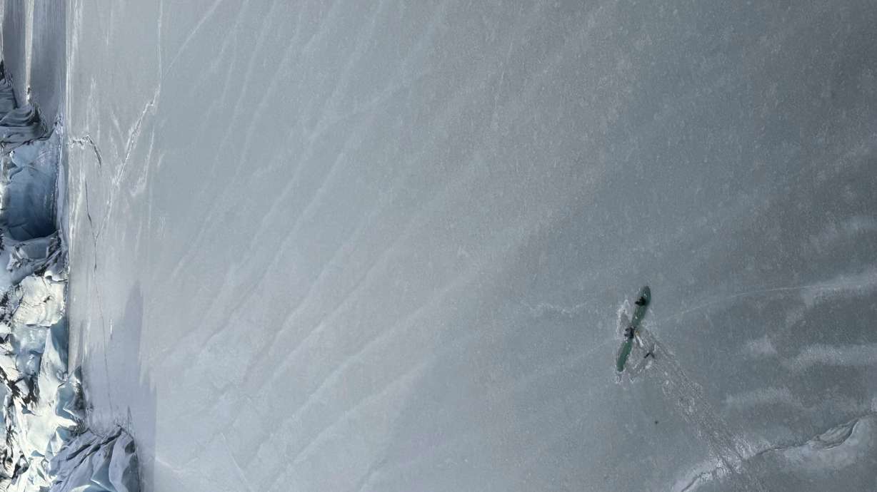 This photo provided Monday by Dale Eicher shows an airplane partially submerged into the ice of Tustumena Lake near Soldotna, Alaska, with the three survivors standing on the plane's wing.