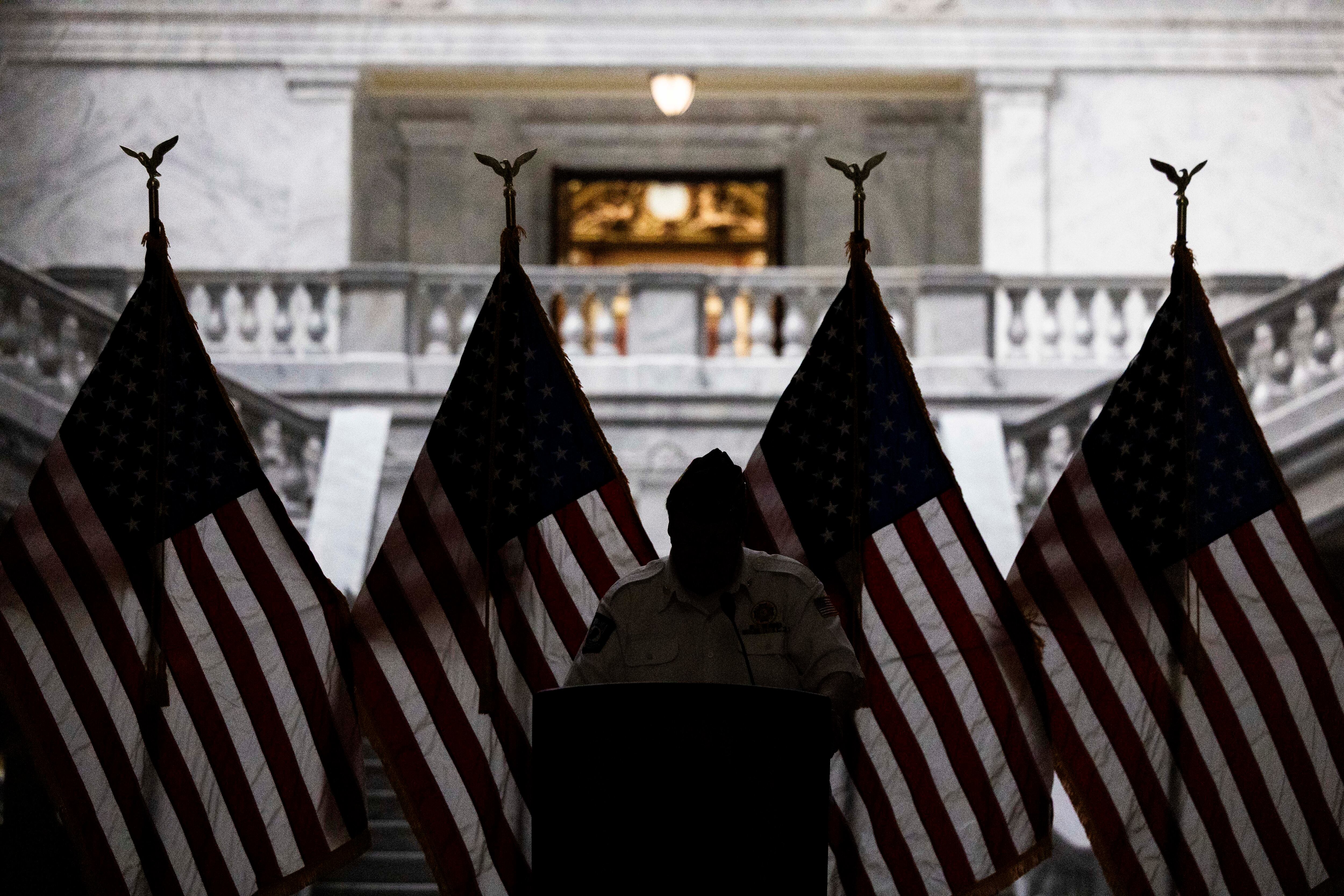 Dennis Parizek, the Veterans of Foreign Wars' state adjutant-quartermaster, is silhouetted with four American flags while he reads Medal of Honor recipient George Edward Wahlen’s citation during a tribute to Utah’s five Medal of Honor recipients on National Medal of Honor Day, where an effort was announced to preserve their legacy through a statewide sculpture initiative, at the Capitol in Salt Lake City on Tuesday. Parizek personally knew Wahlen through the VFW.