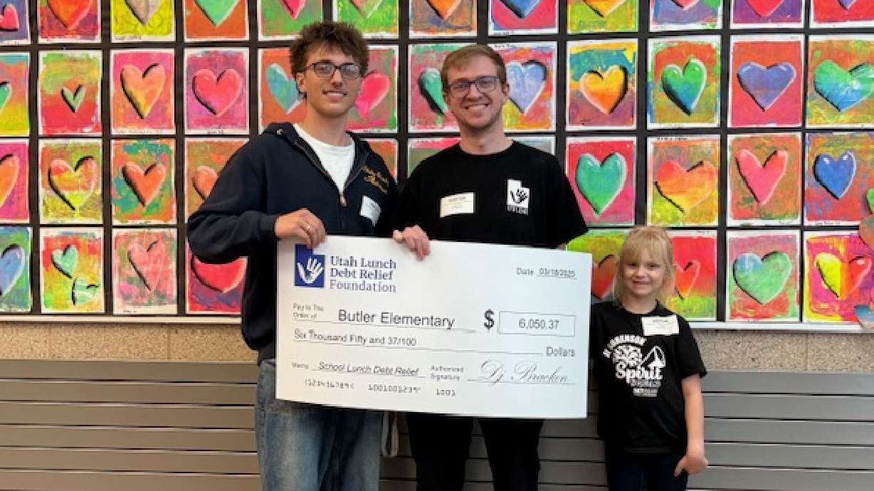 Alta High School student David Van Hafner, left, and Utah Lunch Debt Relief Foundation executive director DJ Bracken, center, present a check to a student at Butler Elementary School to clear the Cottonwood Heights' school's lunch debt.